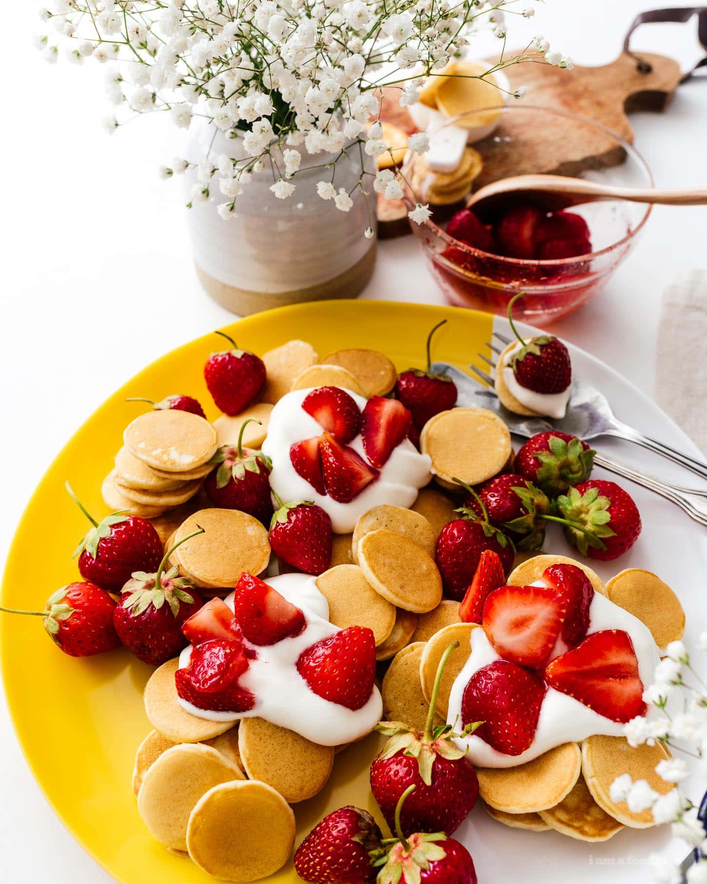 This fluffy mini strawberry shortcake pancake recipe is perfect for summer. Super cute mini silver dollar vanilla pancakes topped with juicy strawberries and softly whipped cream. Like a strawberry shortcake for breakfast! #strawberries #strawberry #strawberrypancakes #strawberrypancake #strawberryshortcake #strawberryshortcakes