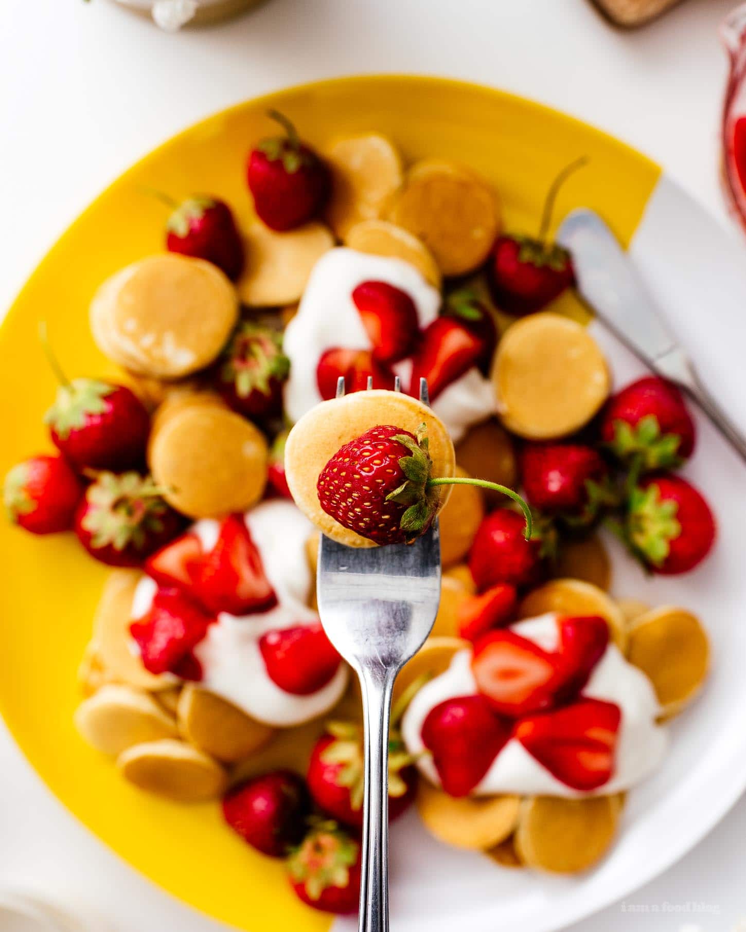 This fluffy strawberry pancake recipe is perfect for summer.  Super cute mini silver dollar vanilla pancakes topped with juicy strawberries and gently whipped cream.  Like a strawberry shortcake for breakfast!  #strawberries #strawberry #strawberry pancakes #strawberry pancakes #strawberry cake #strawberry cakes